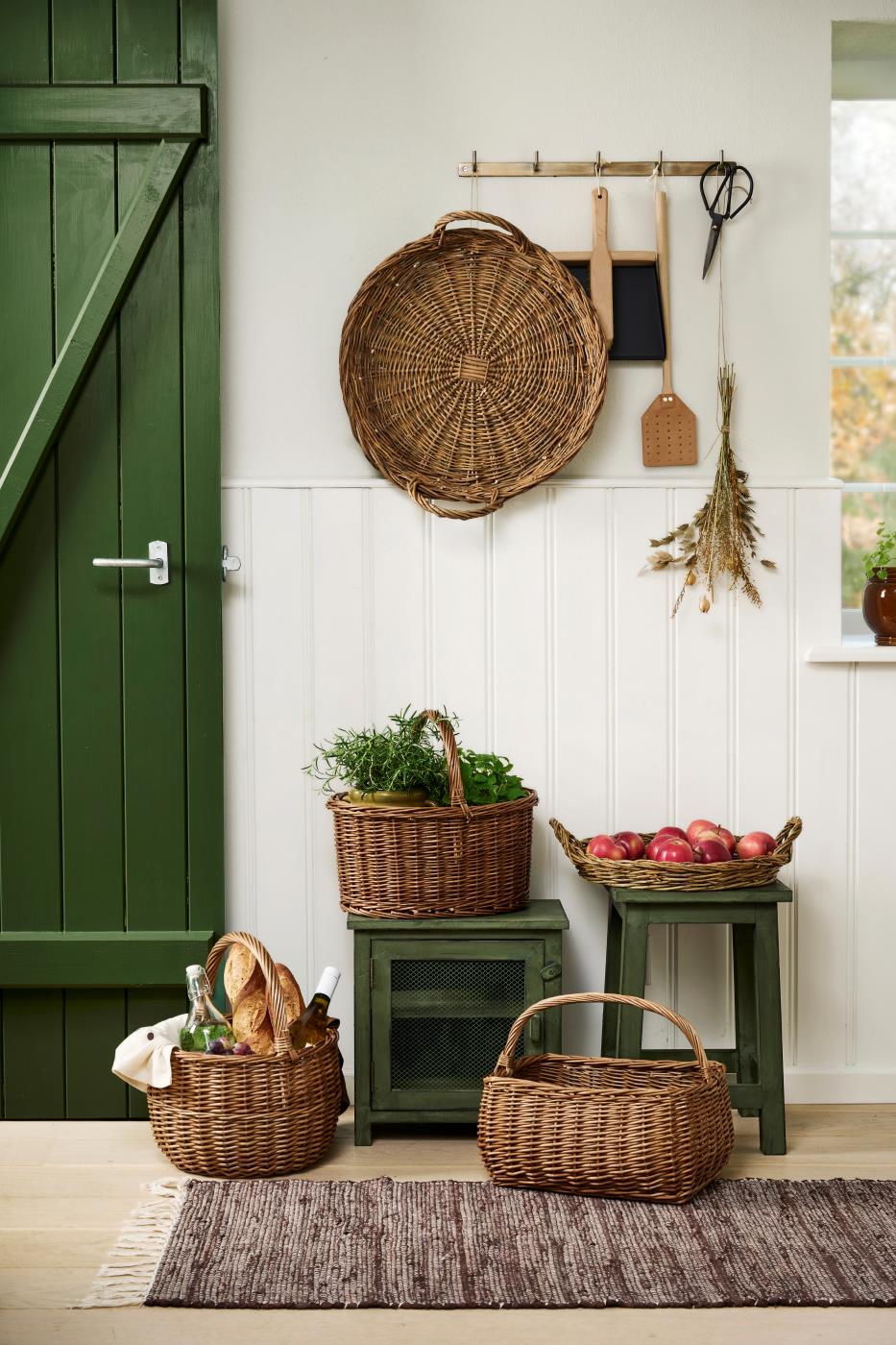 Willow wicker tray from Ib Laursen with apples in a rustic kitchen featuring green furniture and natural materials