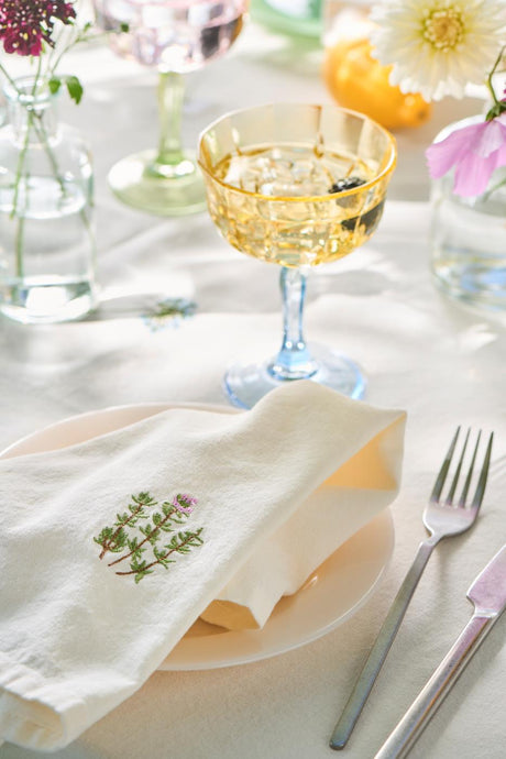 Dækket bord med dug og stofservietter med broderede blomster