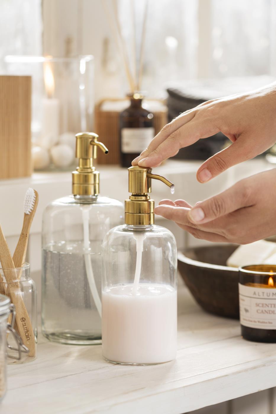 Ib Laursen soap dispenser with brass-colored pump head in use at the sink