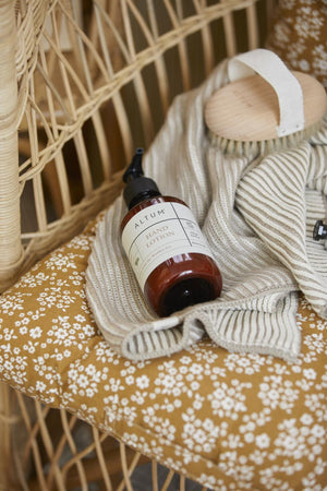 ALTUM care products from Ib Laursen in a woven wicker armchair with textiles and floral details