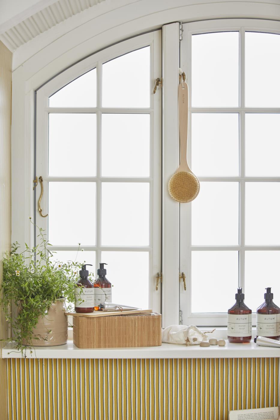 ALTUM care products from Ib Laursen by the window in a bright bathroom with natural materials