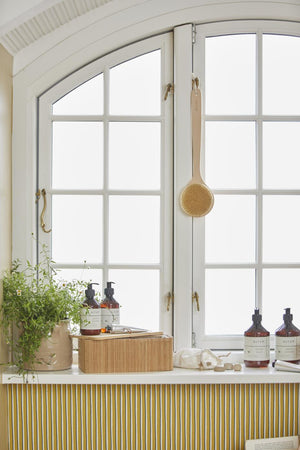 ALTUM care products from Ib Laursen by the window in a bright bathroom with natural materials