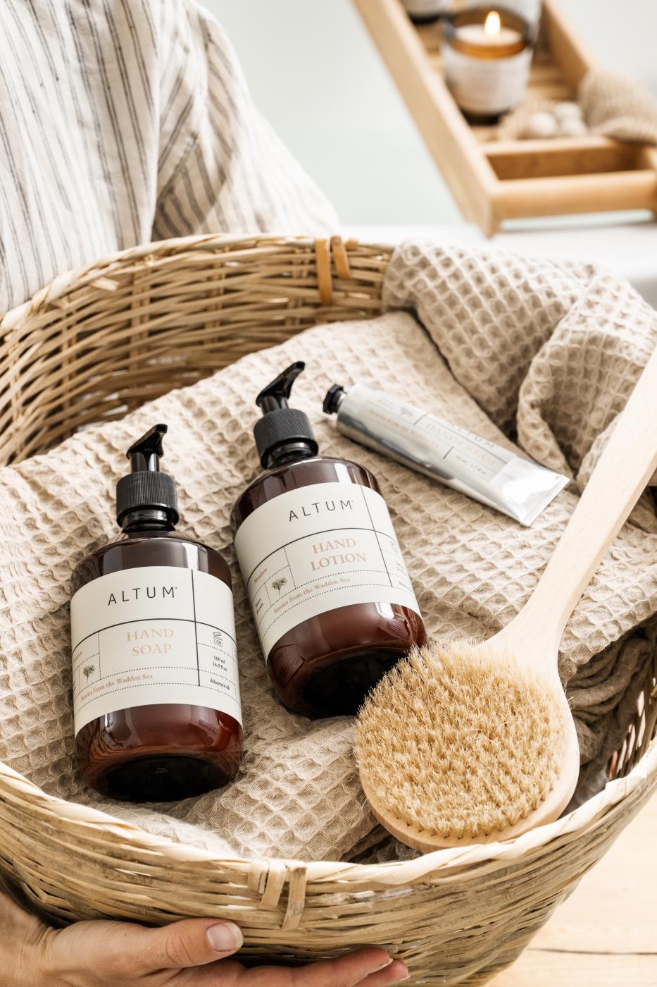 Beige Liseleje towels in a woven basket with bath products and natural materials