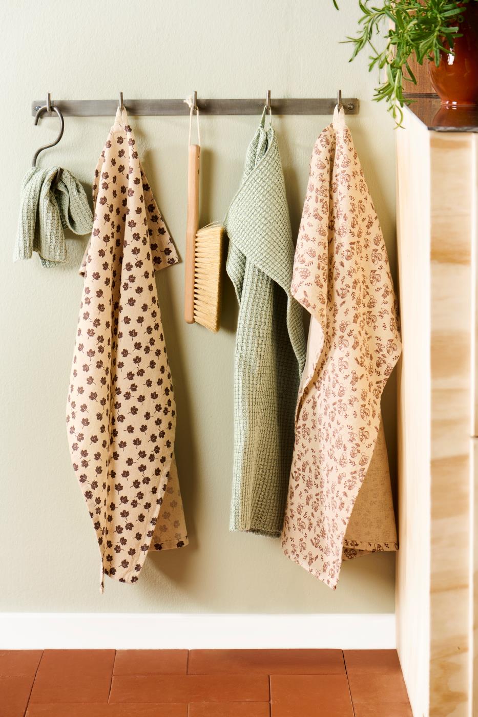 Knitted Mynte kitchen towel and dishcloths from Ib Laursen in assorted colors hanging on a peg rack in the kitchen