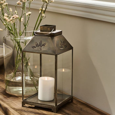 Ib Laursen lanterne med bladformet mønster med levende lyd ved siden af glasvase