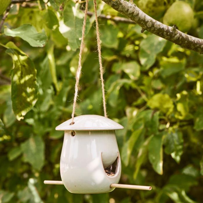 Nærbillede af Ib Laursen fuglefoderhus i askegrå keramik i gren