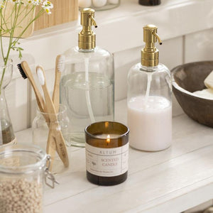 Ib Laursen sæbedispenser glas og messingfarvet pumpe med større dispenser med klar sæbe og et duftlys