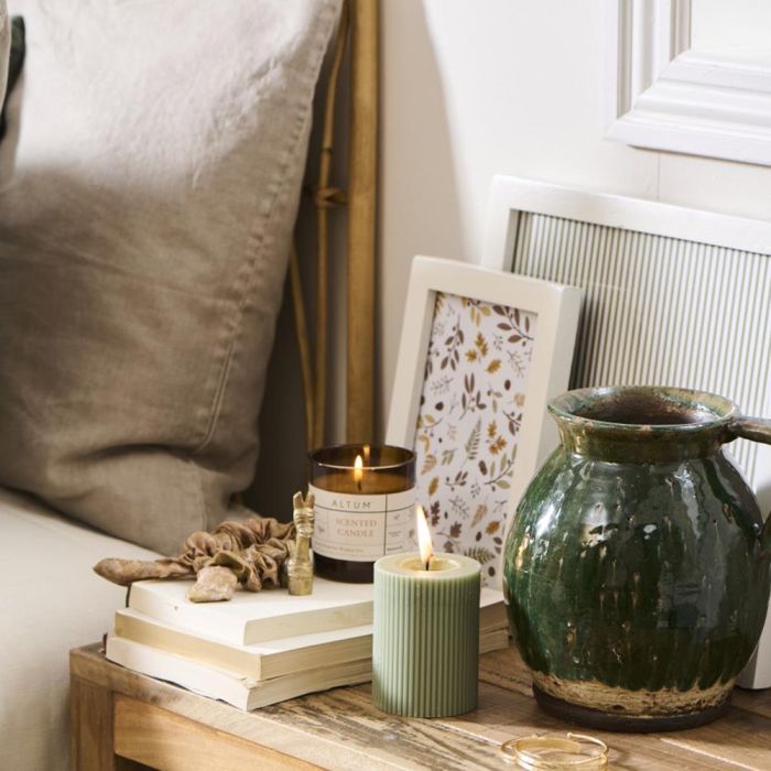 Ib Laursen ALTUM Meadow duftlys i brunt glas på sengebord ovenpå bøger
